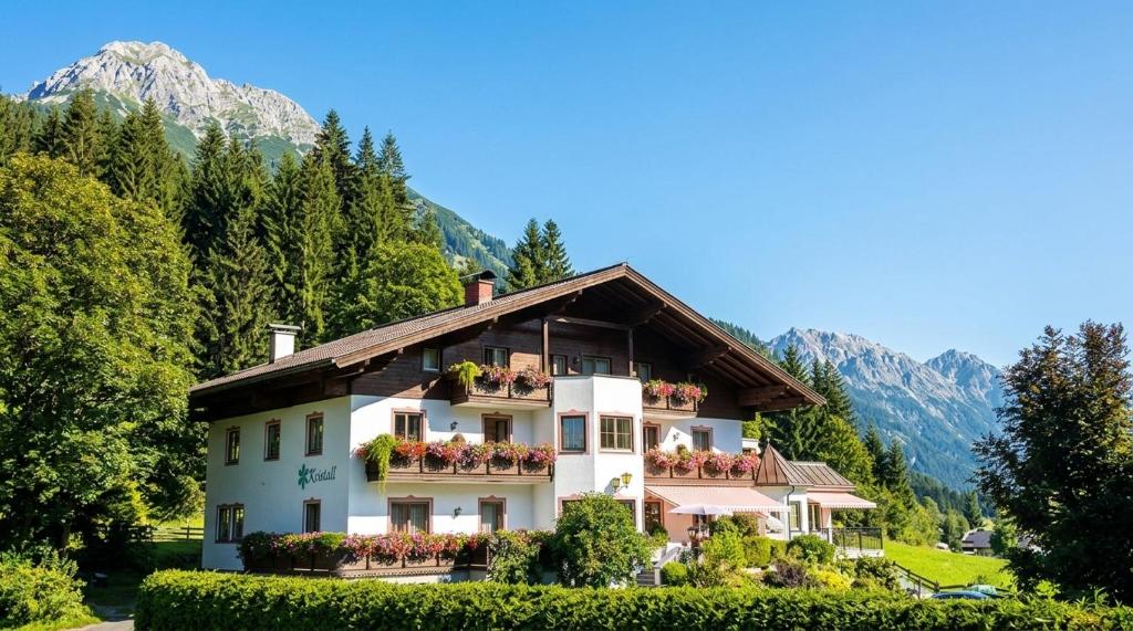 a house with flowers in front of a mountain at Hotel Kristall in Kleinarl