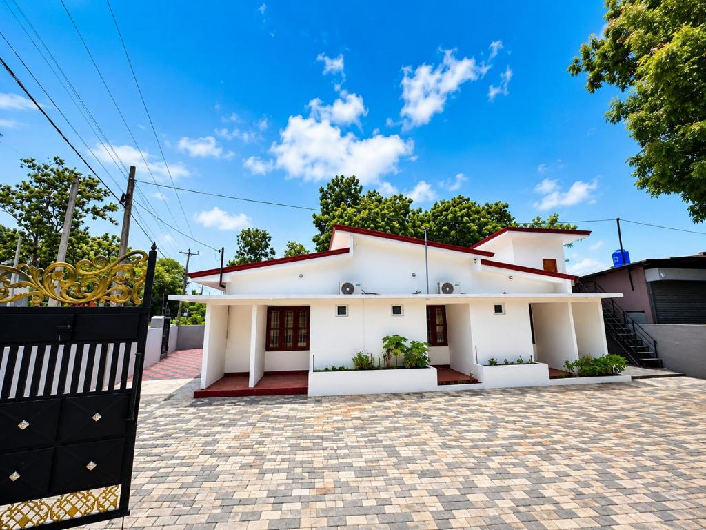a white house with a fence in front of it at JB Vin Hotel in Point Pedro