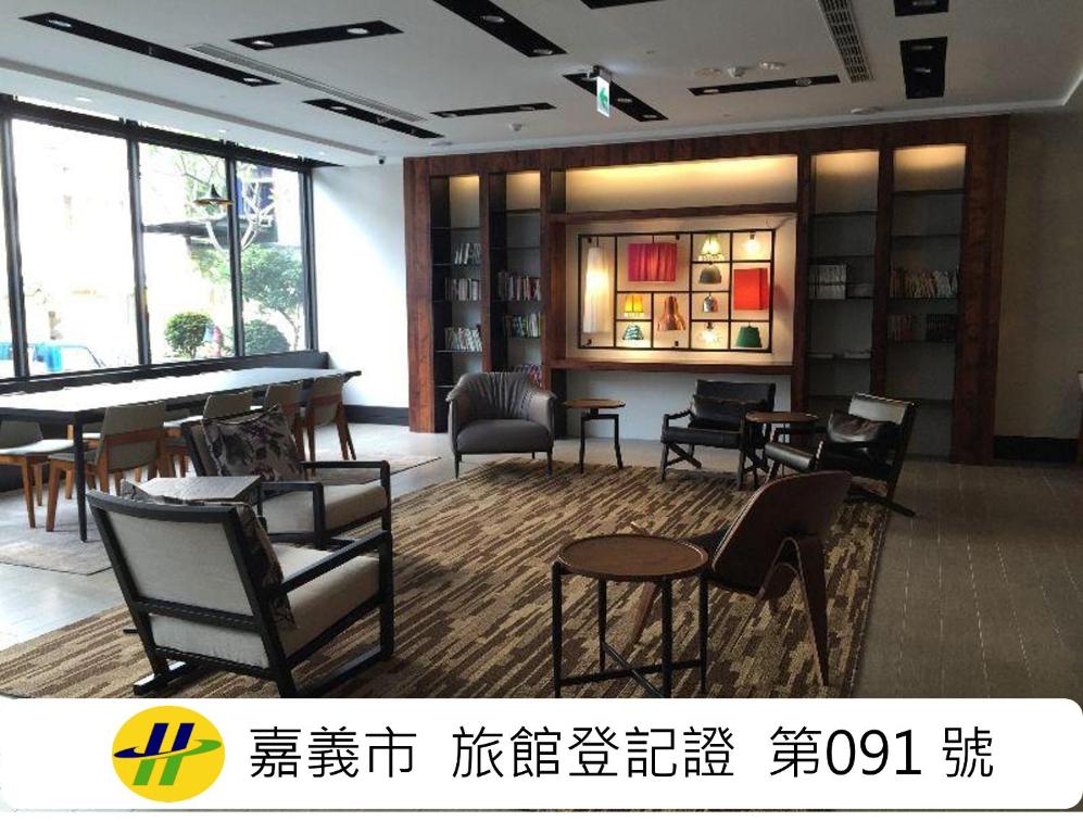 a room with chairs and a table and a piano at Travel Art Inn in Chiayi City
