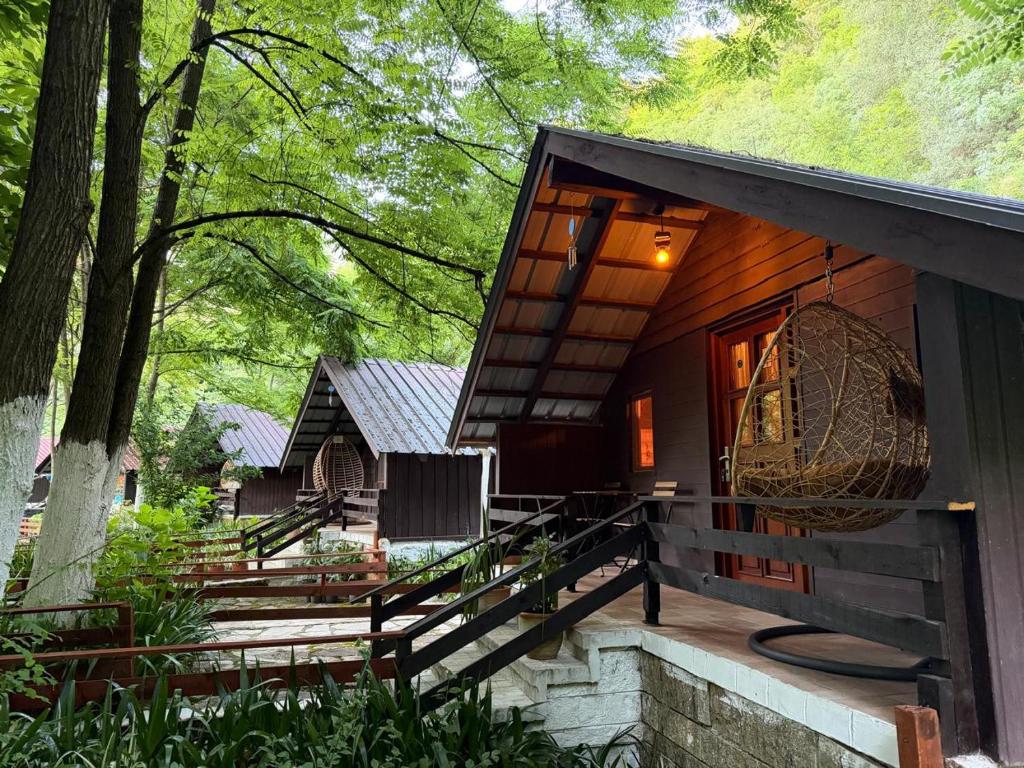 a house in the woods with a porch and a balcony at Blue Eye Villas in Sarandë