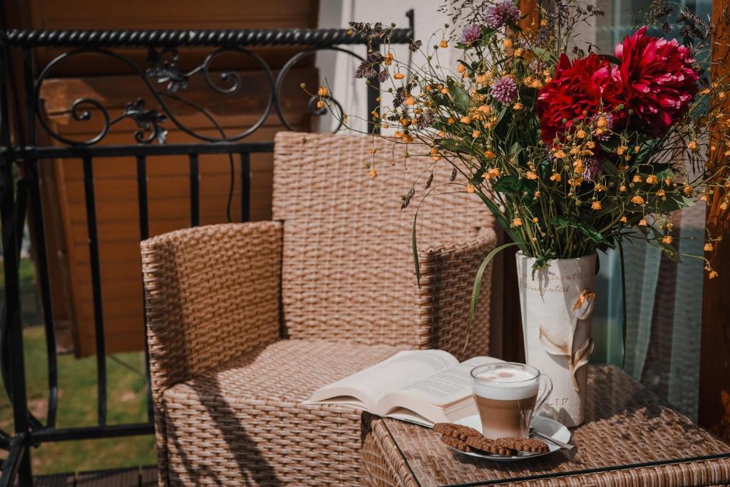a chair with a book and a cup of coffee and flowers at U Hani in Bańska Wyżna