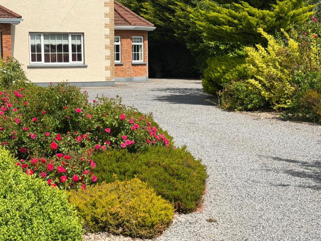 a garden with pink flowers in front of a house at Tunmobi Gardens Apartment in Ballyjamesduff