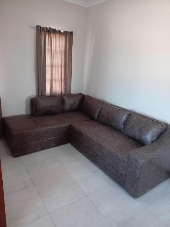 a brown couch in a room with a window at M's guest place Nata in Nata