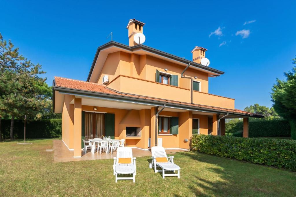 a house with chairs and tables in the yard at Residence Albarella in Isola Albarella