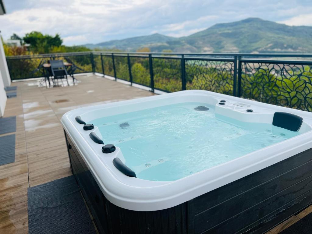 a hot tub on a balcony with a view of mountains at L'évasion in Corent