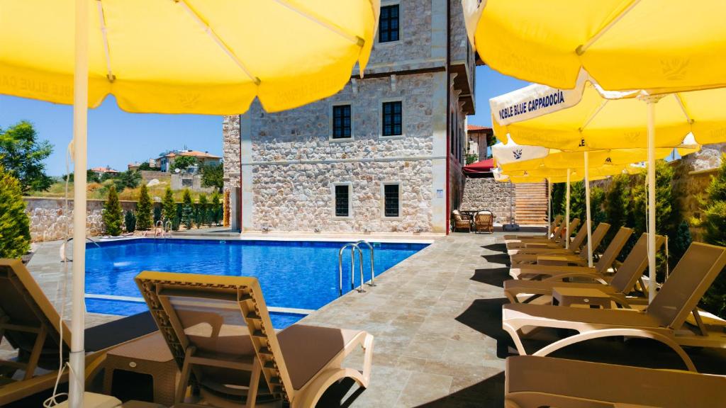 a row of yellow umbrellas and chairs next to a swimming pool at Noble Blue Cappadocia in Ortahisar