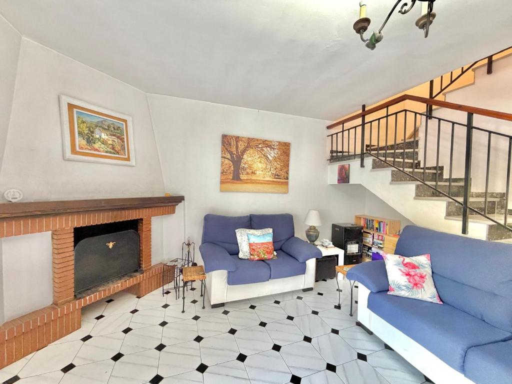 a living room with two blue couches and a fireplace at Terrasol Zayamar in Caleta De Velez