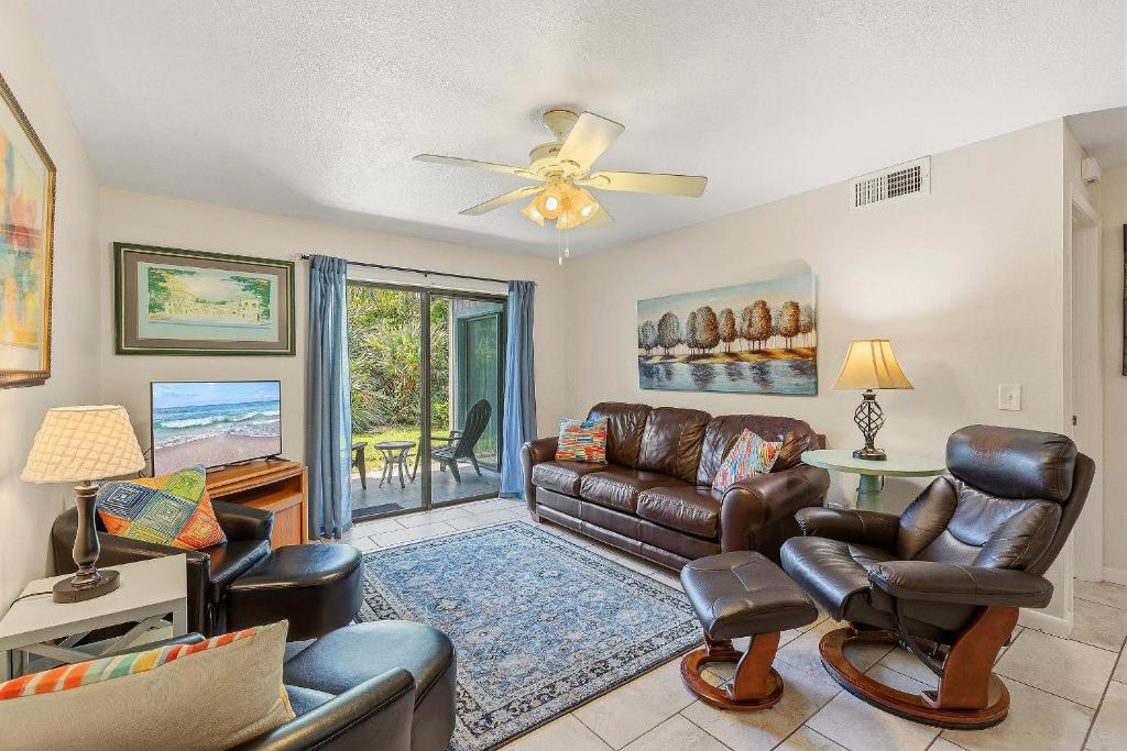 a living room with leather furniture and a ceiling fan at Sea Woods 115 in New Smyrna Beach