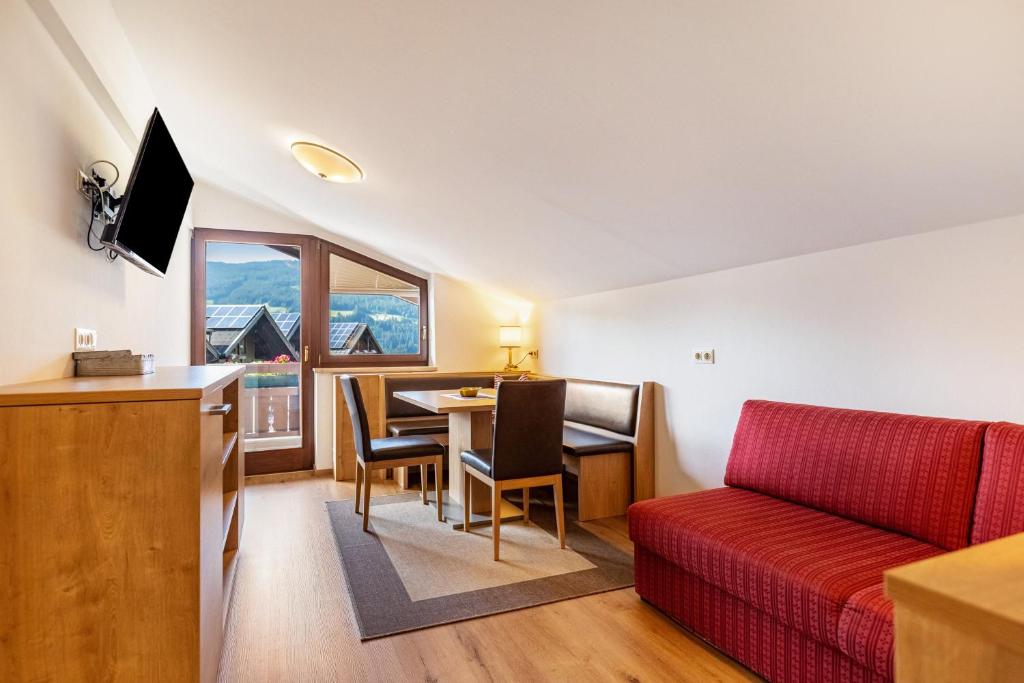 a living room with a red couch and a table at Apartment - Ferienwohnung Elisabeth in Radstadt