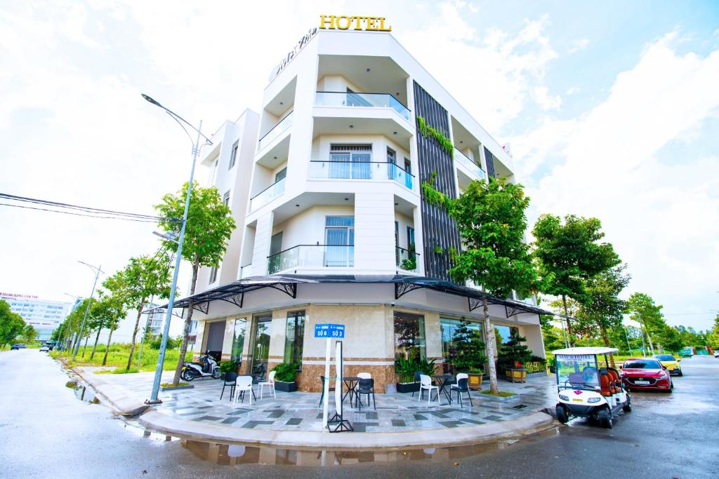 ein weißes Gebäude mit Tischen und Stühlen davor in der Unterkunft May The Hotel in Cần Thơ