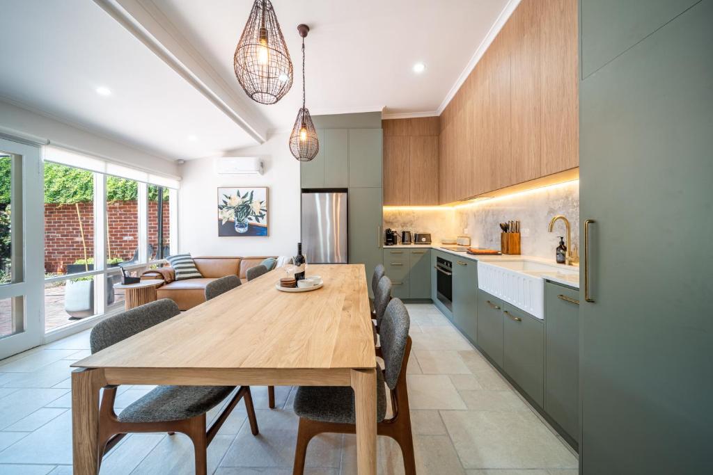 a kitchen and living room with a wooden table and chairs at Wisteria Cottage circa 1880 in North Adelaide