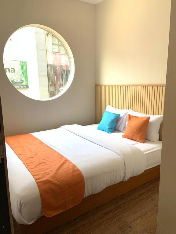 a bed with orange and blue pillows in a room at Sera INN Cikarang in Jatirarangan