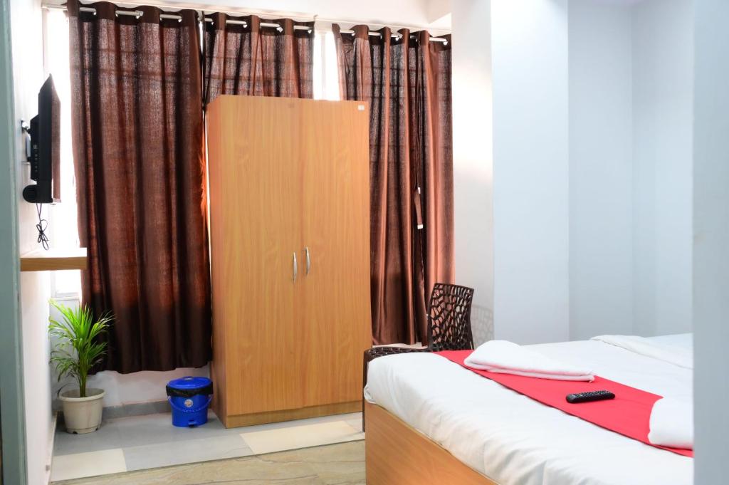 a bedroom with a bed and a cabinet with curtains at Hotel O Westin Regency in Monber