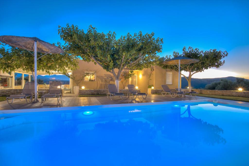 a swimming pool with chairs and umbrellas at night at Nautilus Villa - Private Pool in Elaía