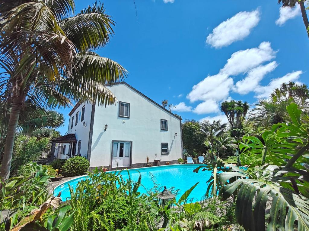 a house with a swimming pool and palm trees at Quinta Minuvida in Rabo de Peixe