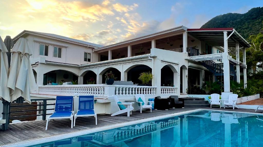 a house with a swimming pool and blue chairs at Quill Gardens Boutique Hotel in Oranjestad