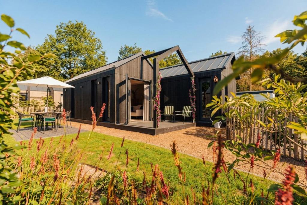 a black house with a garden in front of it at Knus I Tiny house op de Veluwe in Epe