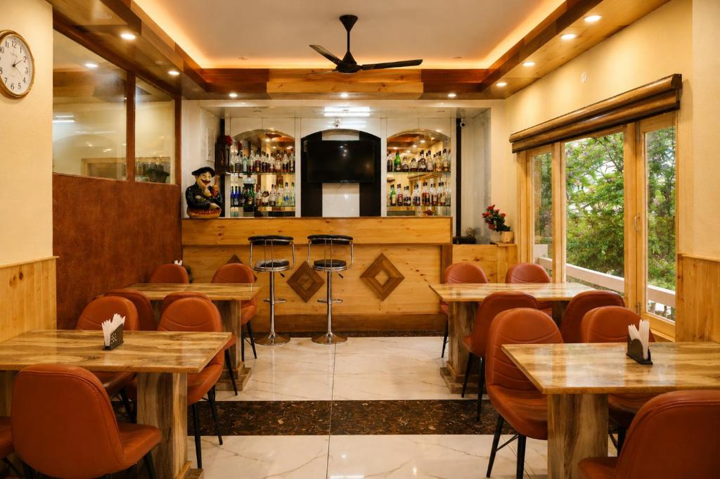 a restaurant with wooden tables and chairs and a bar at Jannat Hotel - Solan in Solan