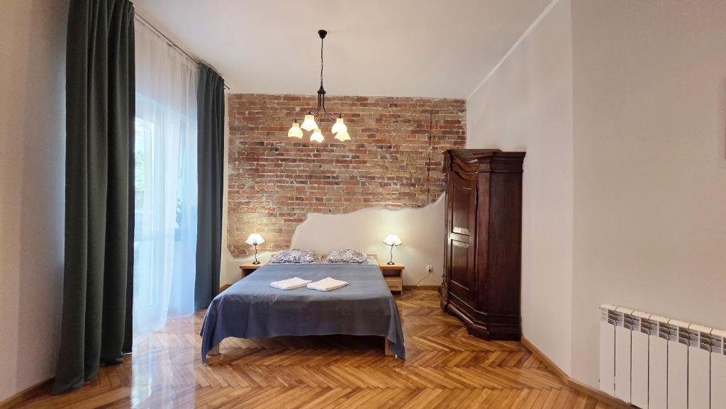 a bedroom with a bed and a brick wall at ENKLAWA Apartamenty in Przemyśl