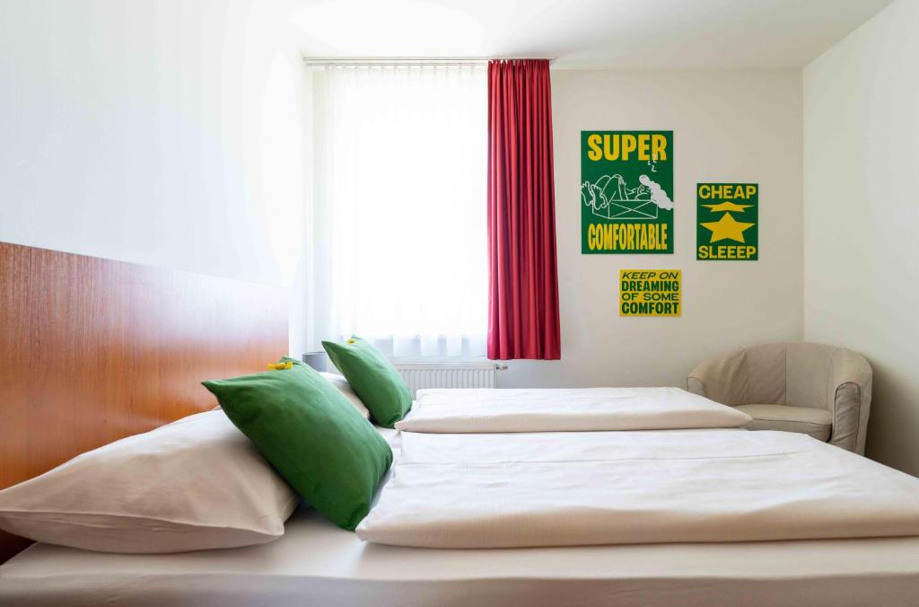 a bedroom with two beds with green and white pillows at SLEEEP Hotel Sattledt in Sattledt