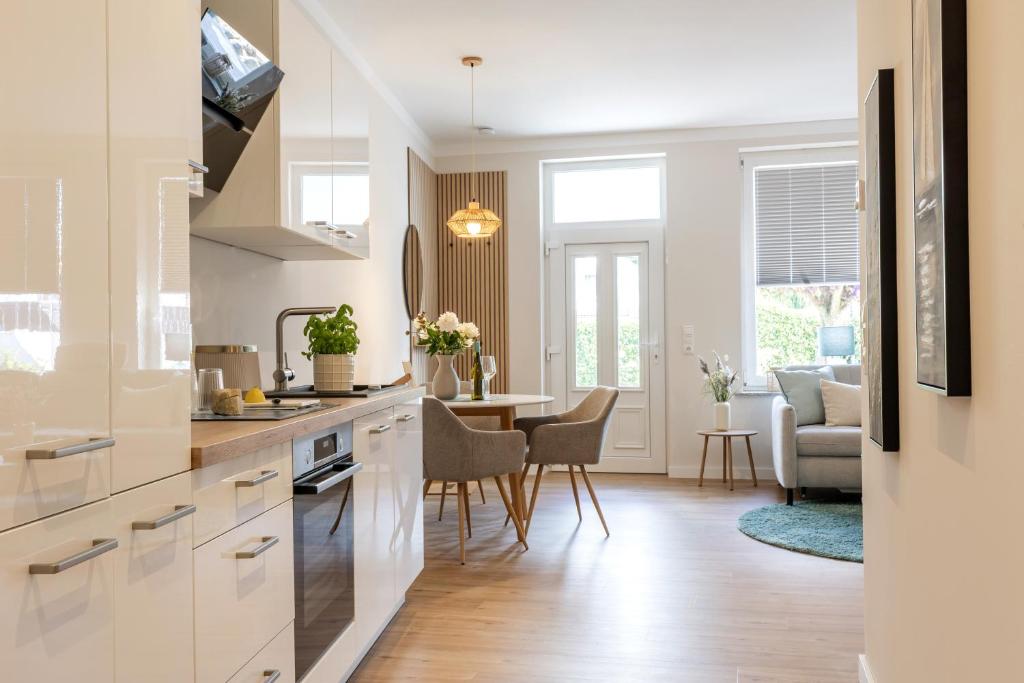 a kitchen with white cabinets and a living room at Mellenthin-Lodges "Seeigel" in Fehmarn