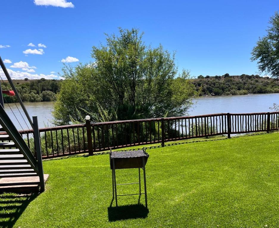 a chair sitting on a lawn next to a fence at Chargo River Lodge in Colesberg