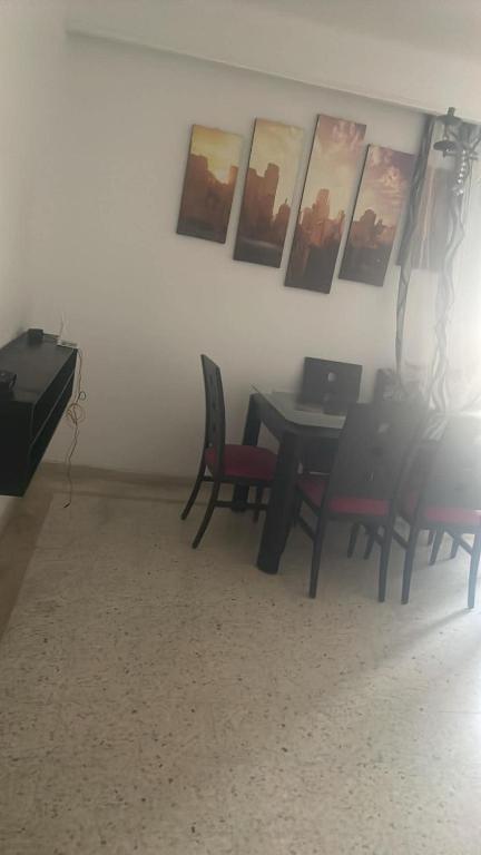 a dining room with a table and chairs and pictures on the wall at Gharbi in Bizerte