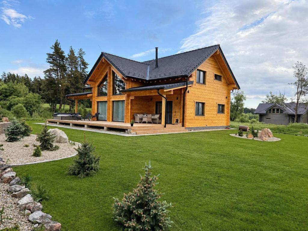 a log home with a large yard with a grassy field at Chatička in Veľká Lomnica