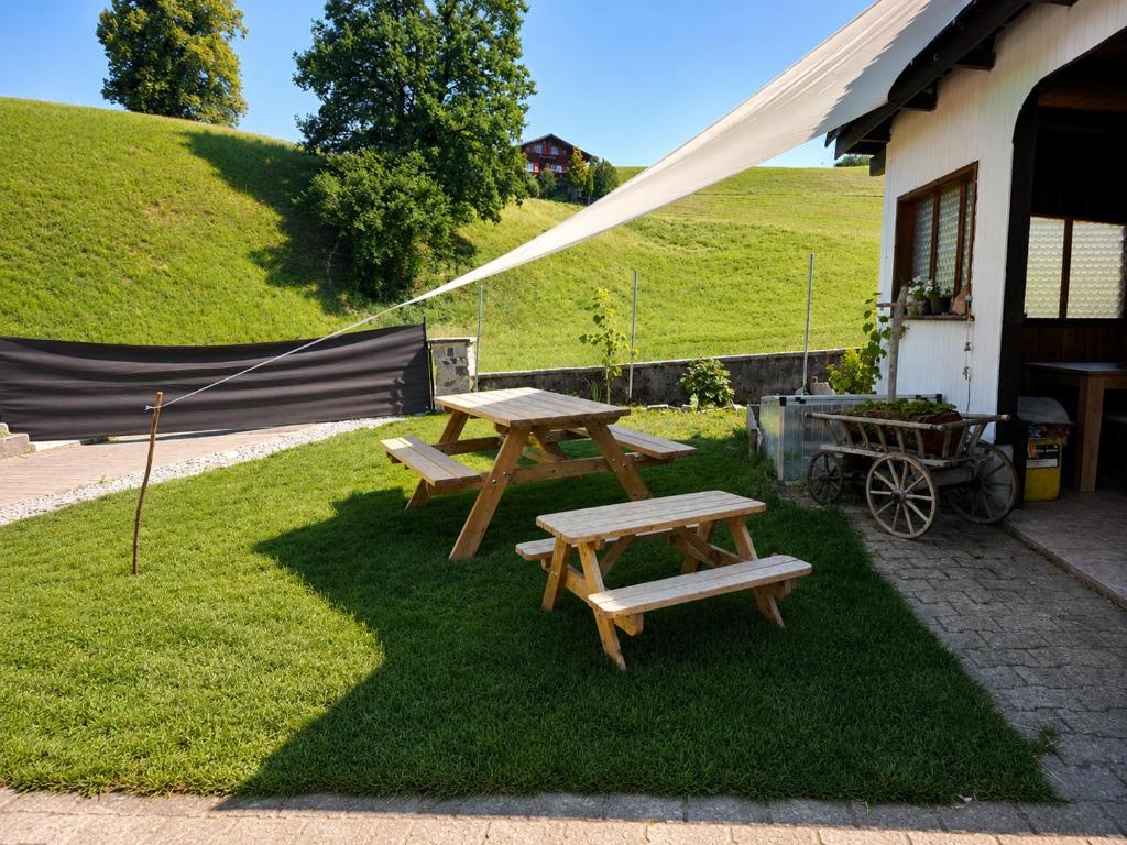 two picnic tables in the grass next to a building at Gackernästli Emmental in Bärau
