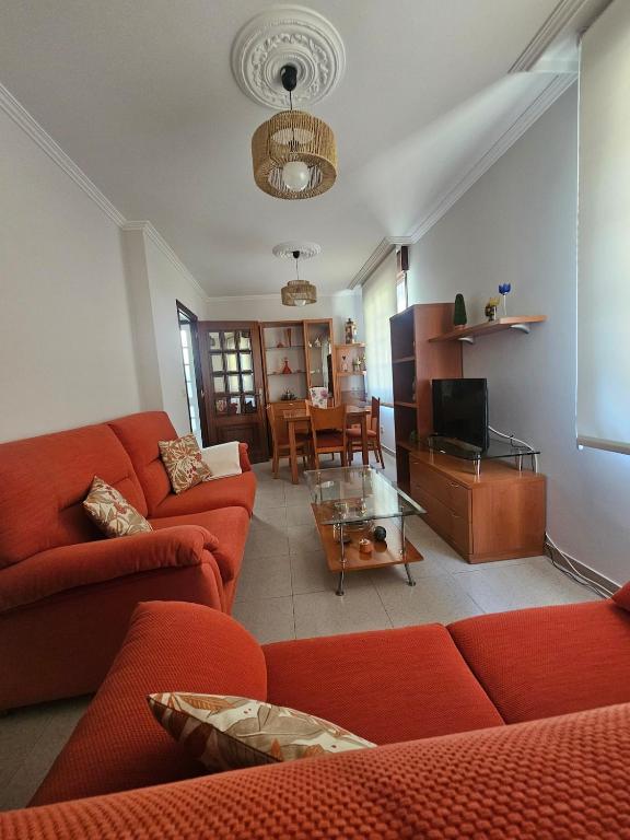 a living room with red couches and a dining room at Casa A devesa in Cangas de Morrazo