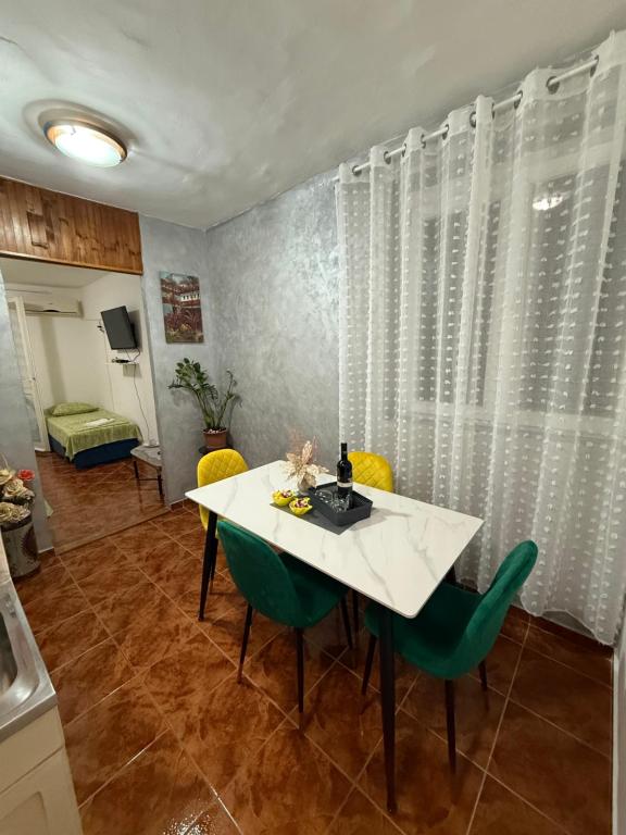 a dining room with a white table and green chairs at Apartman Marković in Meljine