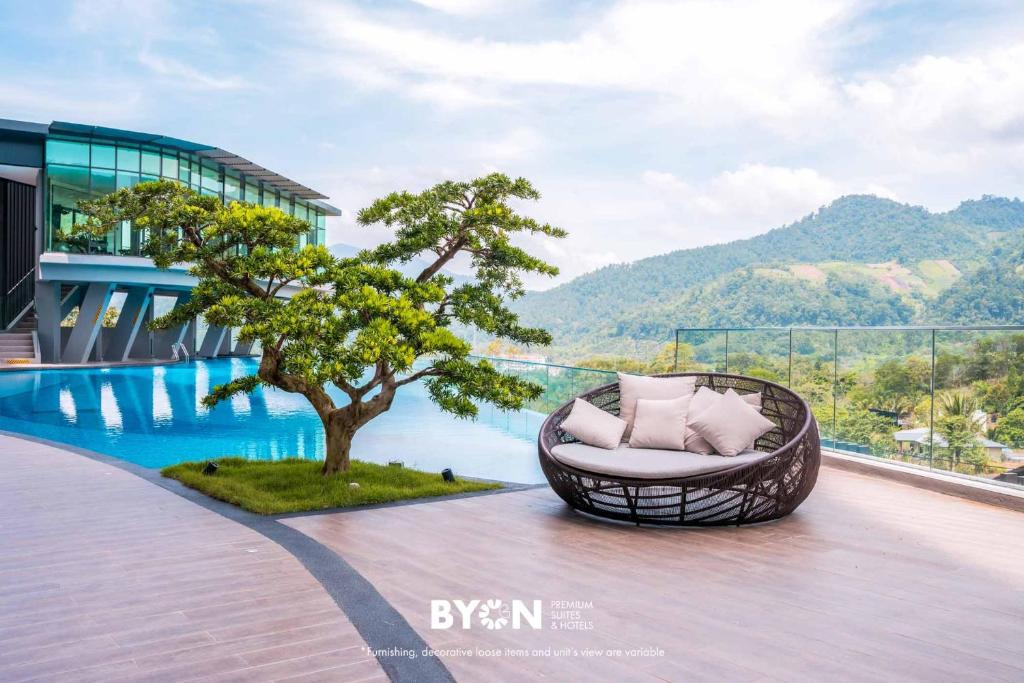 a wicker chair sitting on a deck next to a tree at Enclave Nature Suites Bukit Tinggi by BYON in Bentong