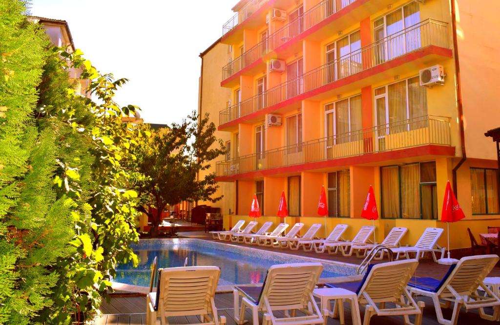 a hotel with chairs and a swimming pool next to a building at Ryor Hotel - Restaurant & Free Parking in Sunny Beach