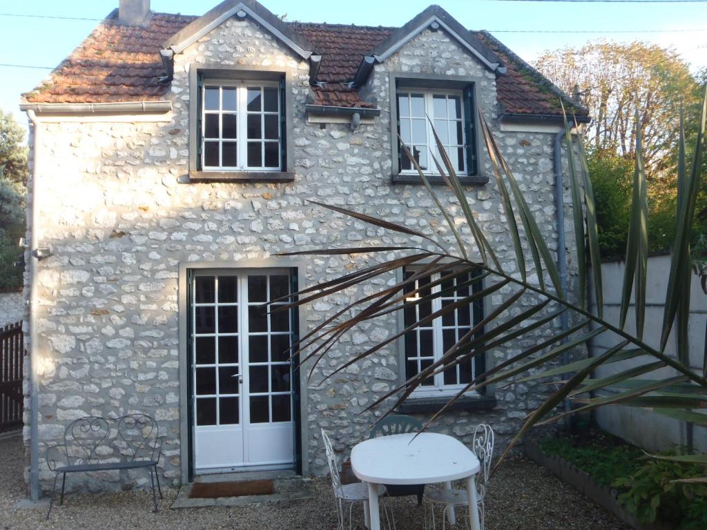 a stone house with a table and chairs in front of it at Les Logis de la Vaucouleurs in Rosay