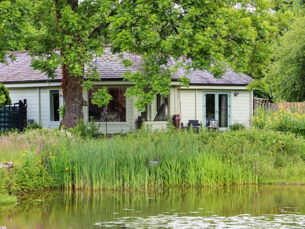 a white house next to a body of water at Bulrush Cabin in Carlisle