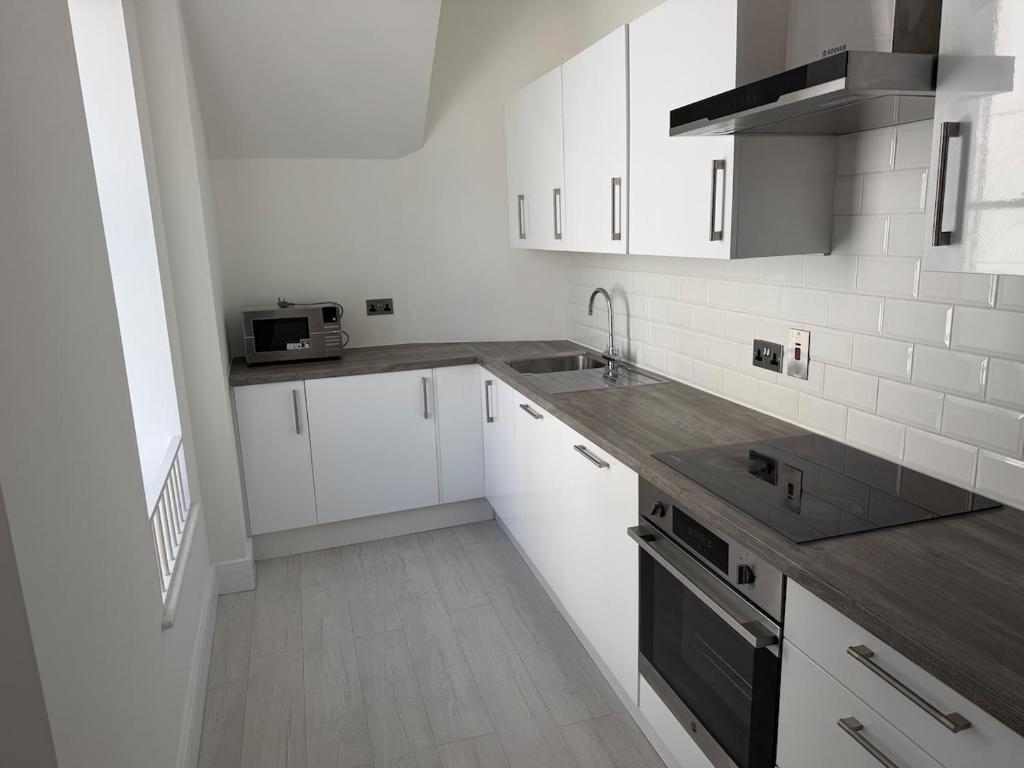 a kitchen with white cabinets and a sink and a stove at 1 bedroom flat in Saint Helier Jersey