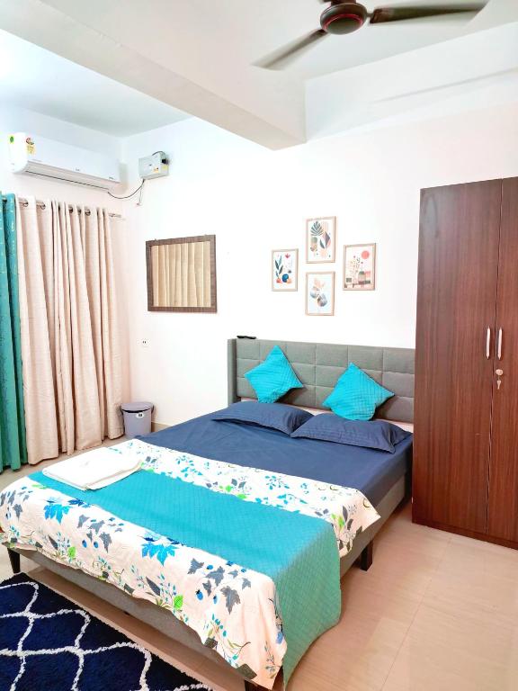 ein Schlafzimmer mit einem Bett mit blauen Laken und blauen Kissen in der Unterkunft Transit Nest 1BHK in Guwahati