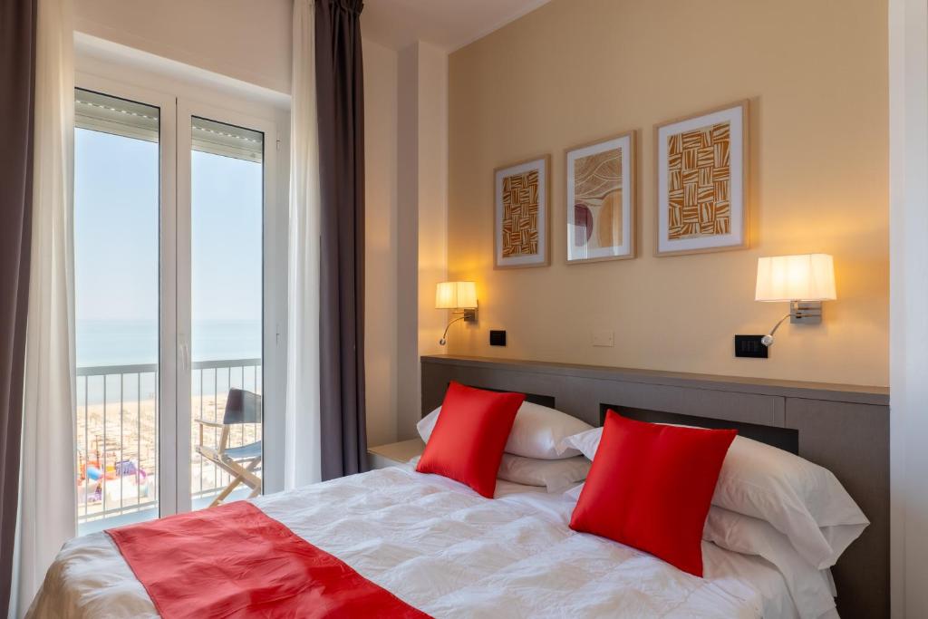 a bedroom with a bed with red pillows and a window at Hotel Continental in Senigallia