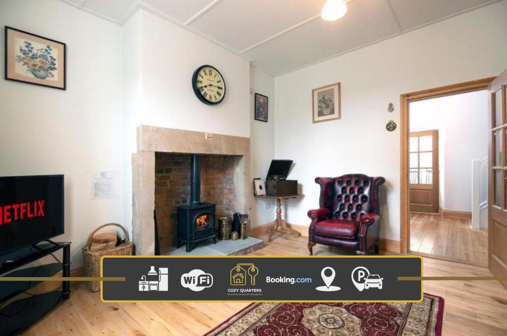 a living room with a fireplace and a chair and a clock at 2 Bedroom Cottage By Cozy Quarters Property Management Holiday Lets Wolsingham Near River Waskerley in Wolsingham