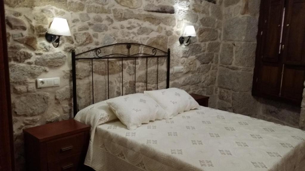1 dormitorio con 1 cama en una pared de piedra en Casa Da Chousa, en Combarro