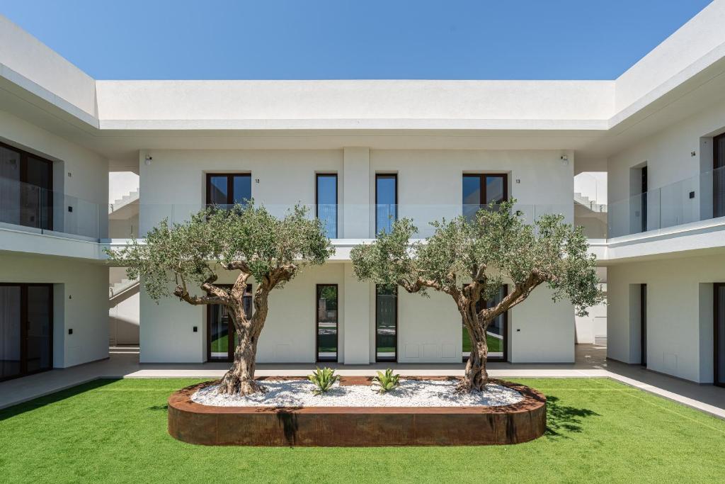an apartment building with two trees in the courtyard at Aura - Stagnone Apartments in Marsala