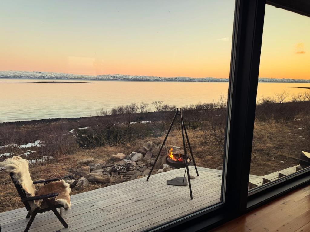 a dog sitting in a chair on a deck looking out a window at Hyggeli in Vadsø
