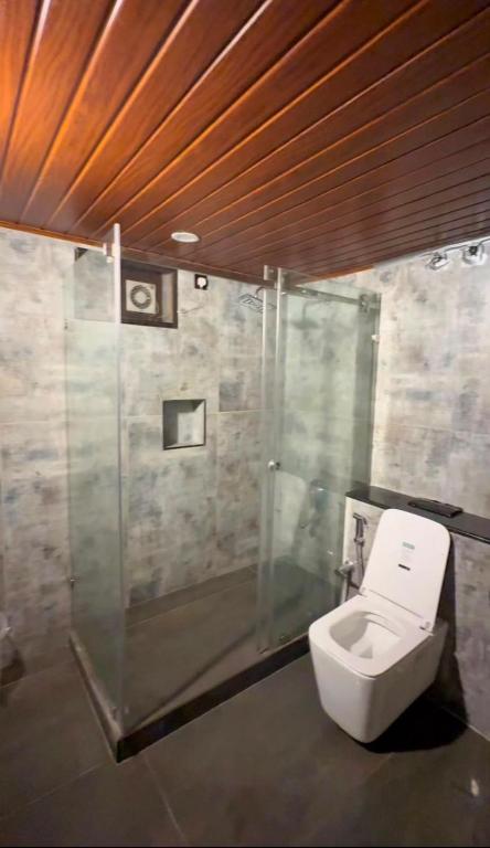 a bathroom with a toilet and a shower at Luxe Kochi Flat Backwater Views in Cochin