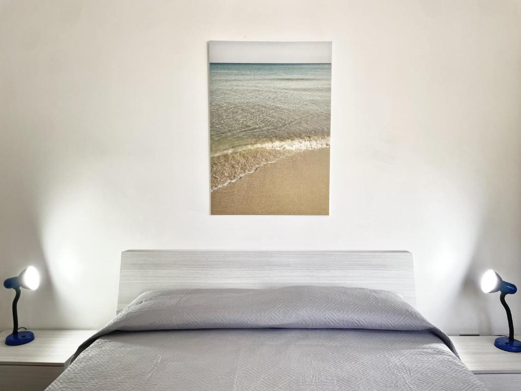 a bedroom with a bed and a picture of the ocean at CASA CALIPSO - Casa a pochi passi dal mare delle Maldive del Salento in Salve