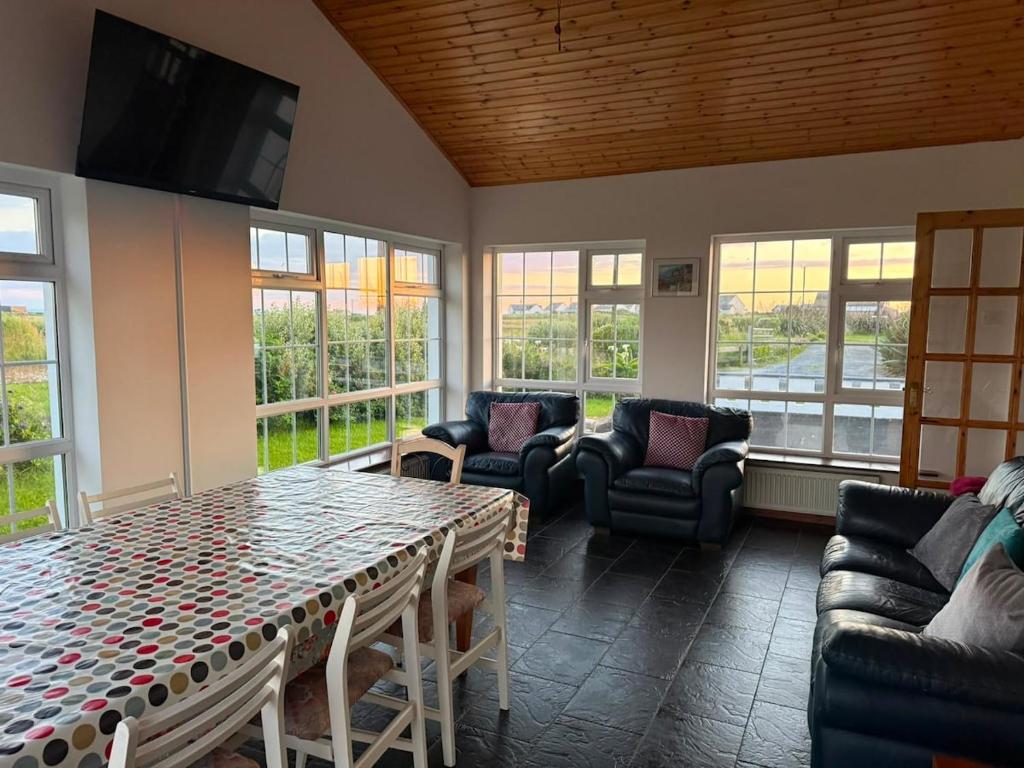 a living room with a table and chairs and windows at Denmar Spacious coastal bungaow in Cleedagh Bridge