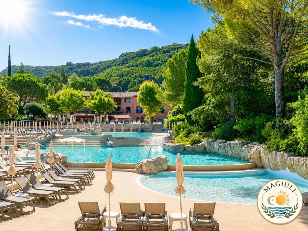 a swimming pool with lounge chairs and a resort at Magiuli Village du Rouret in Grospierres