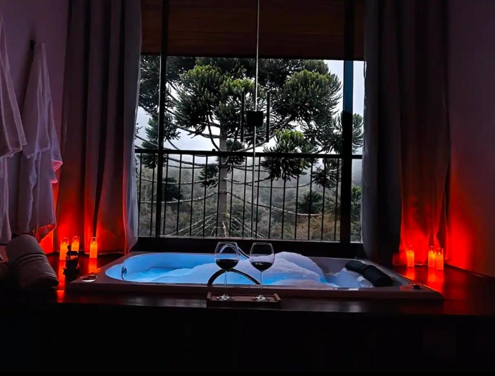 a bath tub with two wine glasses in it with a window at Shoresh Araucária in Campos do Jordão