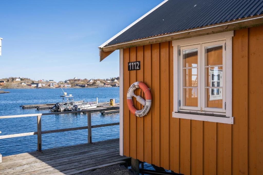 ein kleines Haus auf einem Steg neben dem Wasser in der Unterkunft Åsebua - Renovated rorbu with seaview in Sørvågen