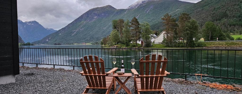two chairs sitting next to a body of water with mountains at Modern lakefront apt with view - EV plug in Stryn