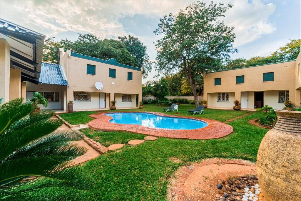 a yard with a pool and two buildings at Guest Paradise Lodge in Victoria Falls